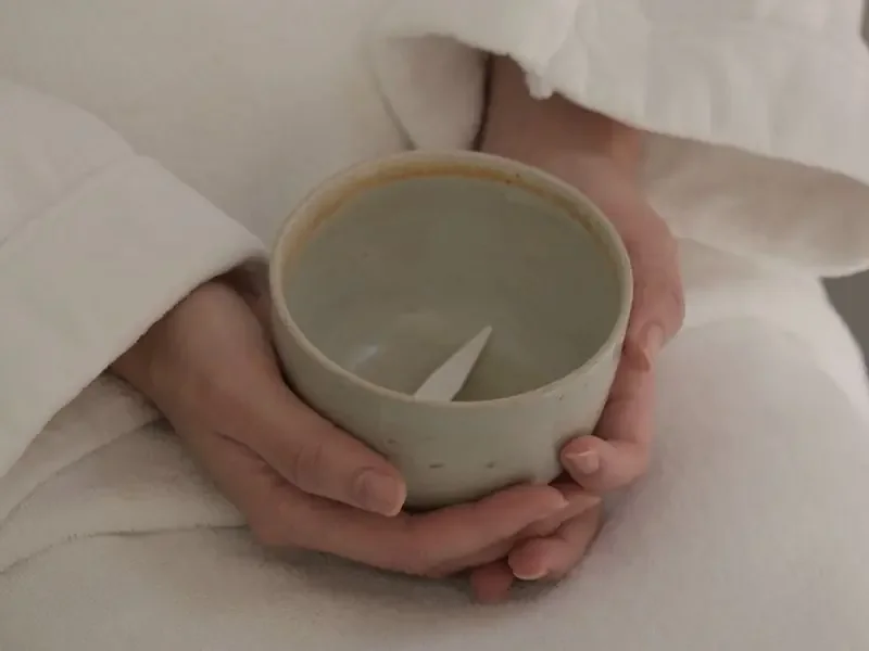 하얀 가운 차림으로 찻잔을 두 손에 감싸 쥔 모습